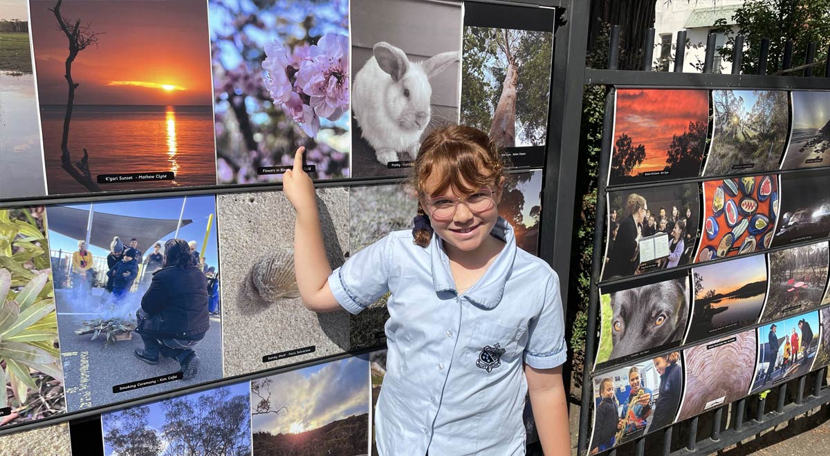 Isy Gold (year 2) points to her photograph, Flowers in Bloom, part of the exhibition.