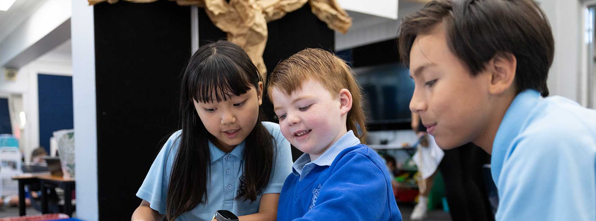 St Canice's student being assisted by Year 6 buddies. The student is writing in his booklet.
