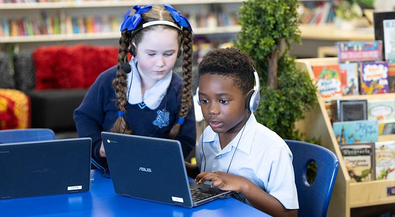 St Canice's Katoomba students in school library, learning off of their laptops and wearing headphones.