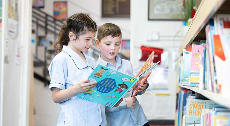 St Canice’s Katoomba students picking library books off of shelf