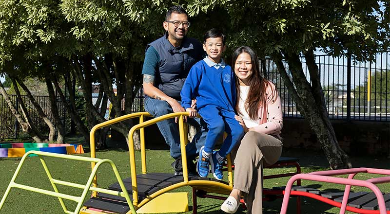 Parents and student at St Canice's Katoomba sitting on play equipment